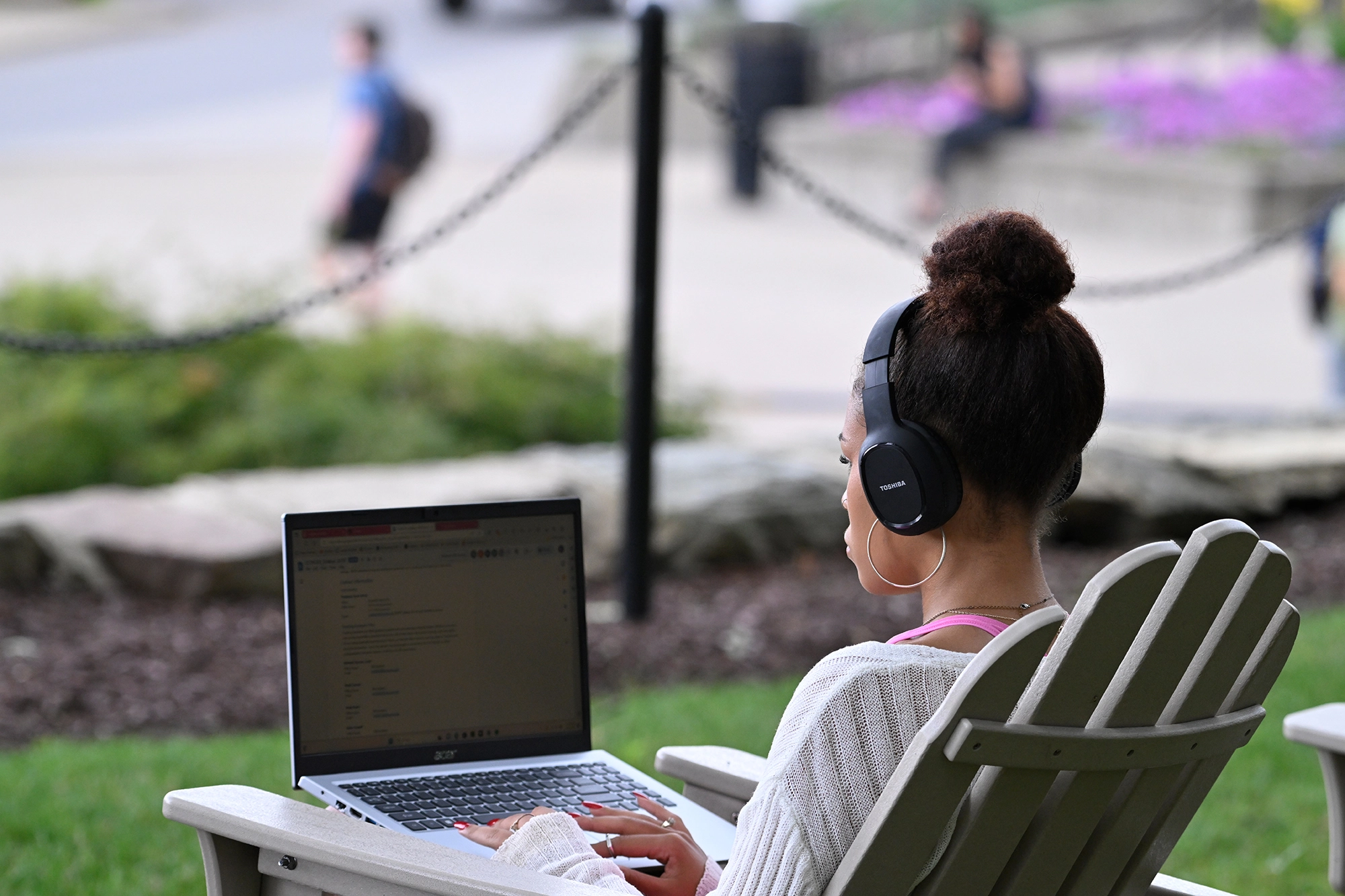 A student working outside on their laptop in a lawn chair